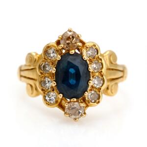 Safir- og diamantring af 14 kt. guld prydet med oval facetslebet safir omkranset af talrige enkelt- og old mine-cut diamanter. Str. 49. Æske medflg. Ca. 1950-60