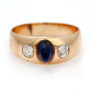 Safir- og diamantring af 14 kt. guld prydet med oval høj cabochonslebet safir flankeret af to old mine-cut diamanter. Str. 64. Ca. 1960-70.