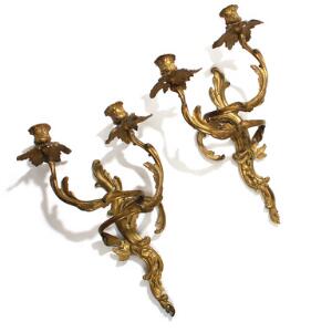 Et par franske rococo væglampetter af forgyldt bronze, støbt med blomster og bladværk, hver med to svungne lysarme. 18. årh. H. 41. 2