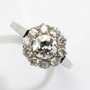 Diamantring af 14 kt. hvidguld prydet med brillantslebet diamant på ca. 0.80 ct. omkranset af talrige brillantslebne diamanter på i alt ca. 0.60 ct.