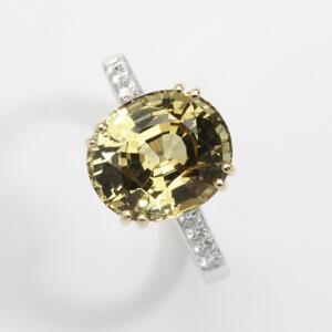 Krysoberyl- og diamantring af 18 kt. hvidguld prydet med oval facetslebet intens grøngul krysoberyl på ca. 6.00 ct. og talrige talrige brillantslebne diamanter.