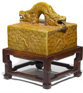 Stort kinesisk segl af brændt ler med strågul glasur, firsidet med drager i relief, hank i form af drage. Kina, 19. årh. Og stand af træ.