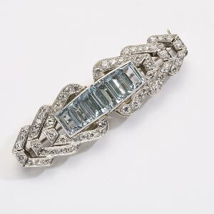 Akvamarin- og diamantbrocheclips af platin og hvidguld prydet med facetslebne akvamariner og talrige enkelt- og brillantslebne diamanter. L. 5,5 cm. Ca. 1950.
