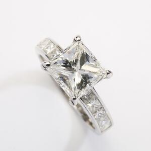 Diamantring af 18 kt. hvidguld prydet med prinsesseslebet diamant på ca. 3.30 ct. flankeret af talrige prinsesselebne diamanter. Str. 53. Ca. 2007.