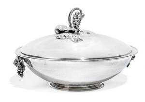 Georg Jensen Lågterrin af sterlingsølv, smedet med lågknop samt hanke i form af bladværk og drueklaser. Vægt 1383 gr. L. 24,3.