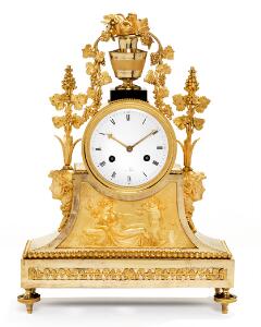 Fransk Louis XVI kaminur af forgyldt og patineret bronze, prydet med vase, vinløv og maskaroner, hvid emaljeret skive. Sign. á Paris. 18. årh.s slutning. H. 45.