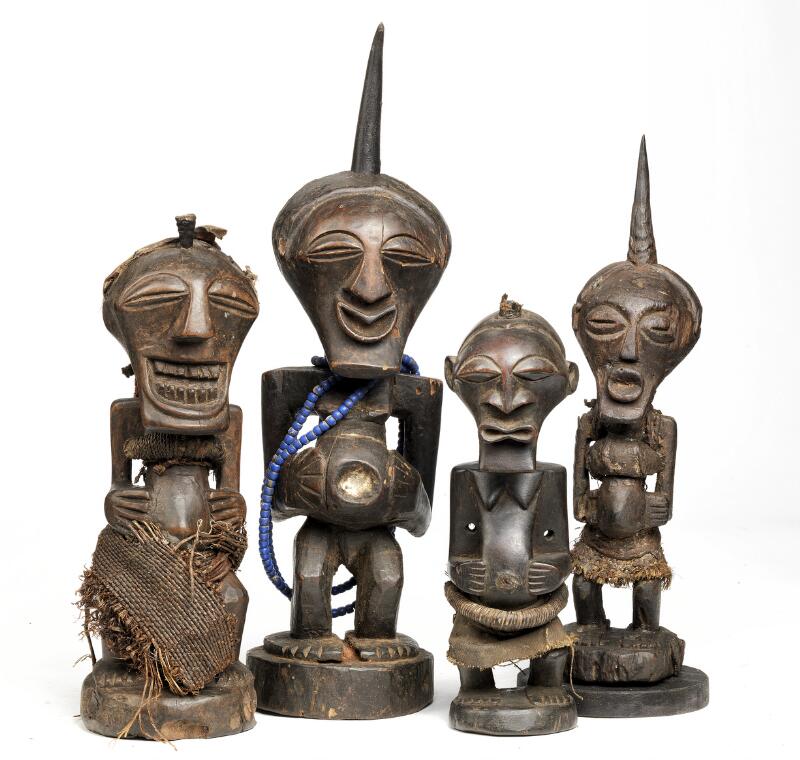 Four fetish figures of carved patinated wood. One decorated with blue...