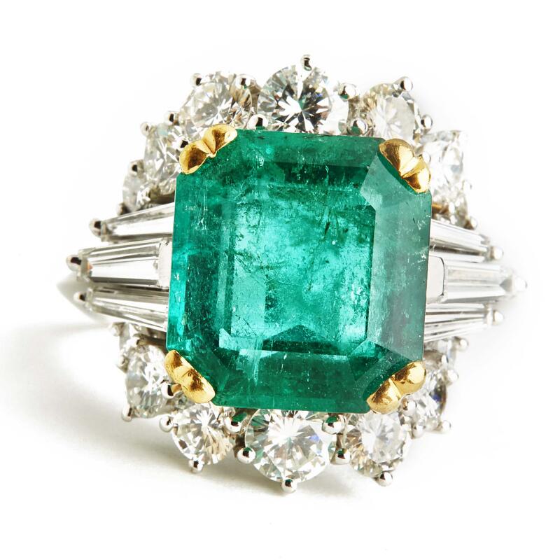 An emerald and diamond ring set with an emerald-cut emerald encircled ...
