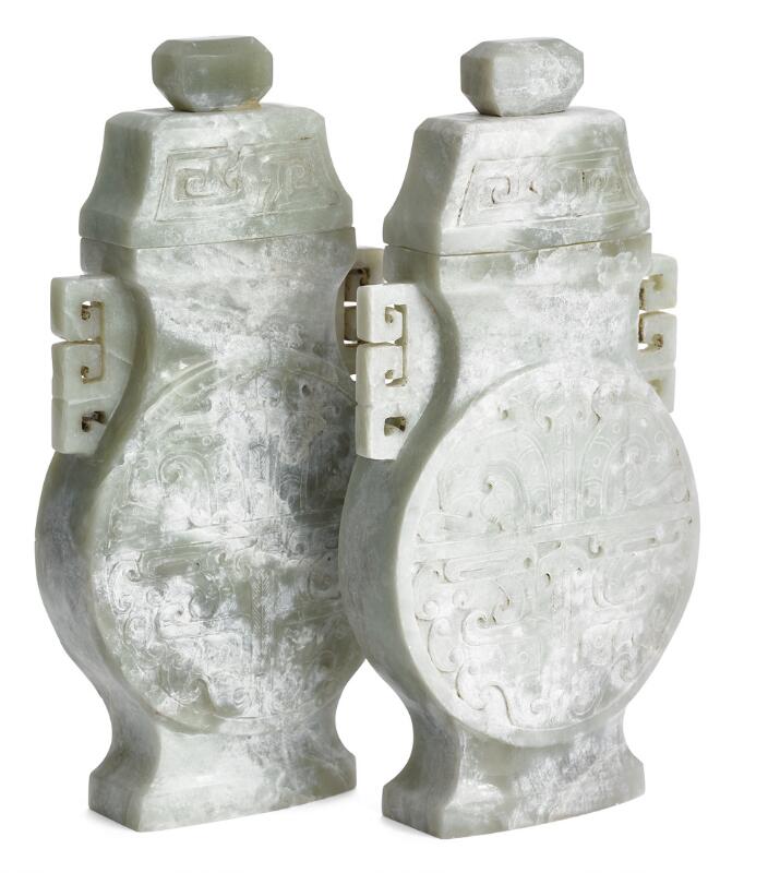 A pair of Chinese lidded vases of greenish jade carved in archaic style...