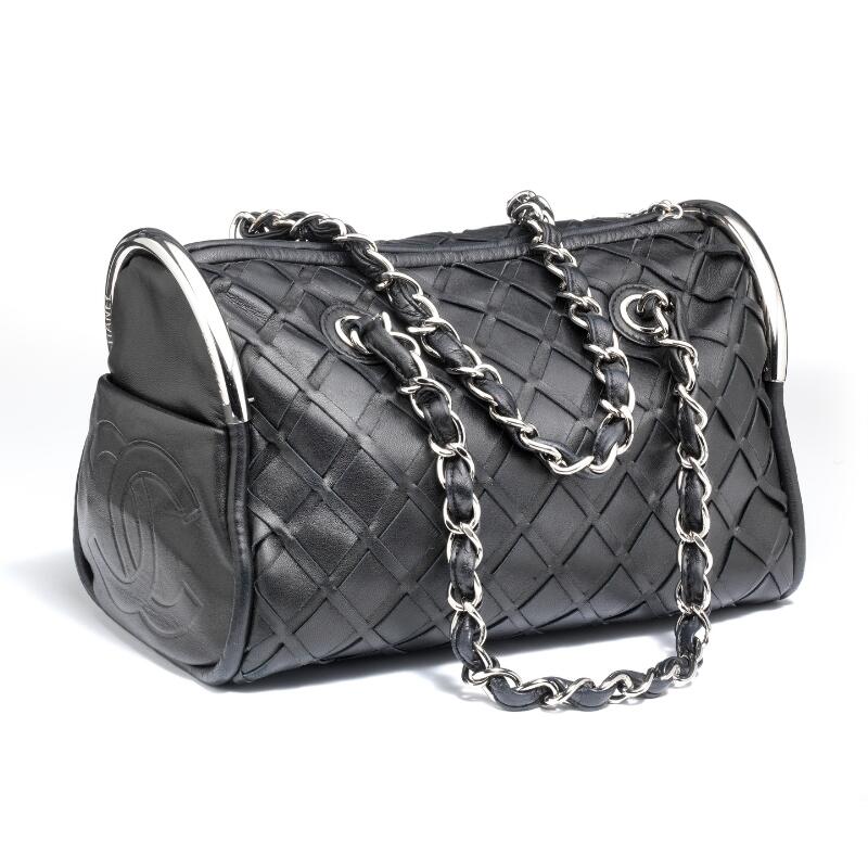 Chanel: Taske af sort læder med sølvfarvede beslag, to kædehanke og et lynlås – Bruun Rasmussen Kunstauktioner