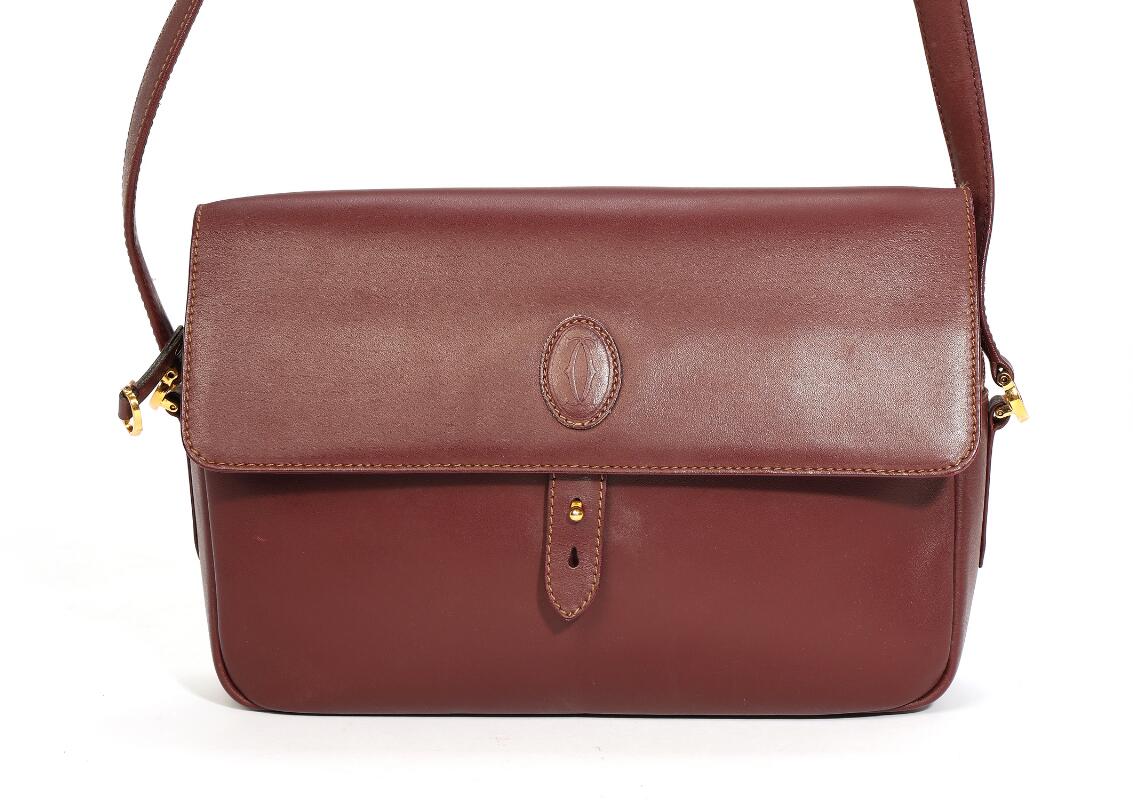 Cartier: A bag of burgundy leather with gold tone hardware