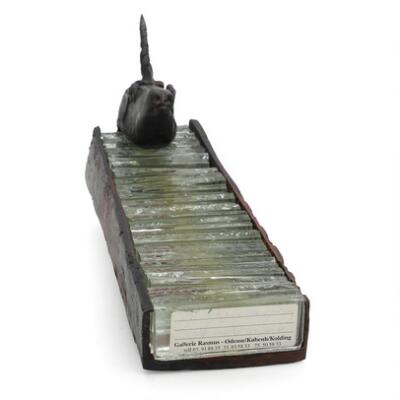 Unicorn head in patinated bronze, mounted on a rectangular base of bronze and glass. Late 20th century. H. 27.5. W. 9. D. 4 cm.