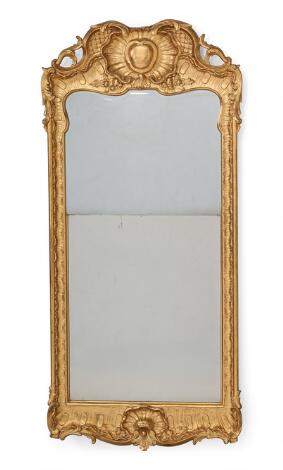 A Swedish Rococo mirror in frame of gilded wood, two-part faceted mirror glass, the back with lacquer stamp. Mid-18th century. H. 146 cm. W. 66 cm.